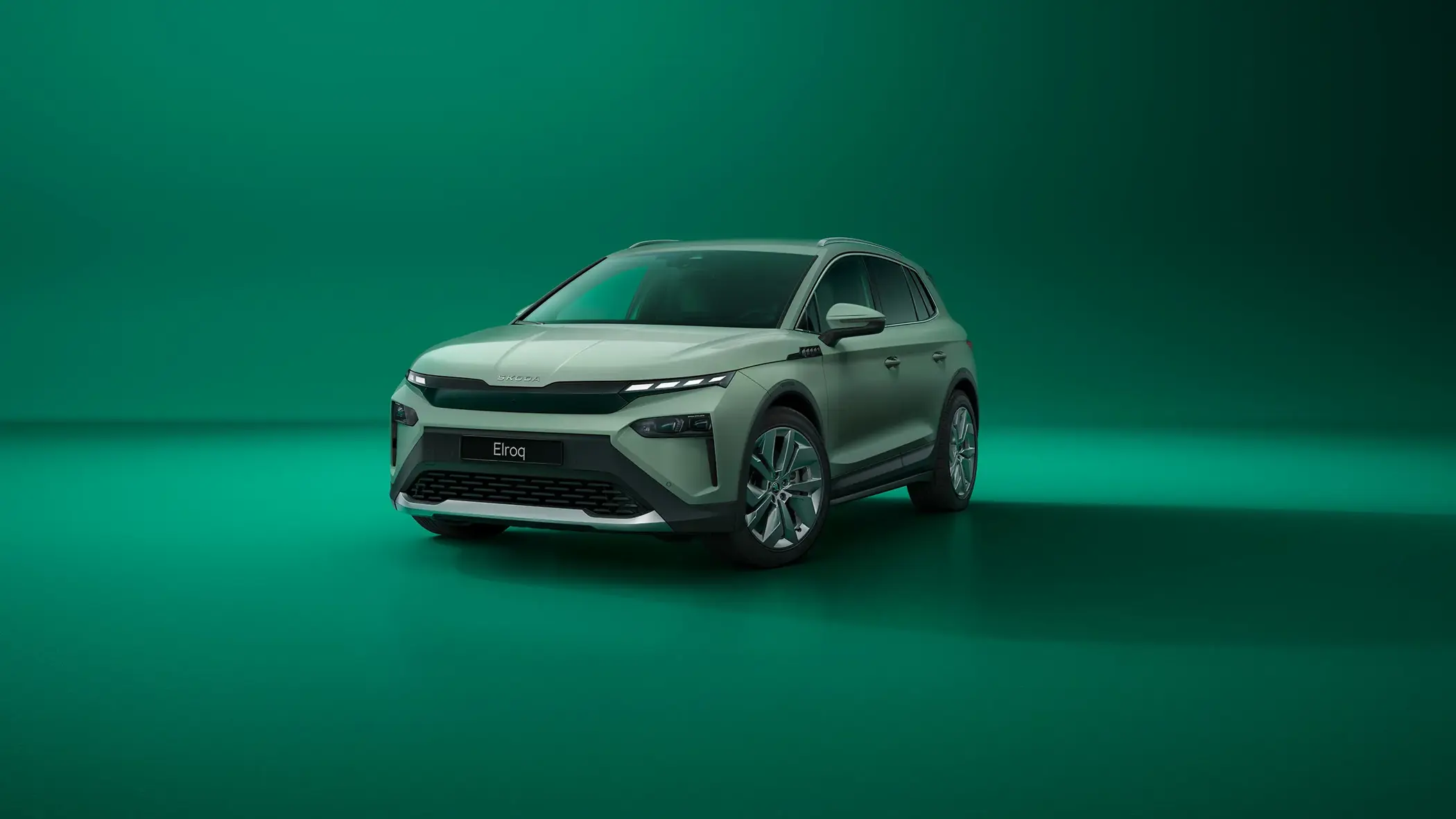 Skoda Elroq SUV vist skråt forfra i et studie med ensfarvet grøn baggrund.